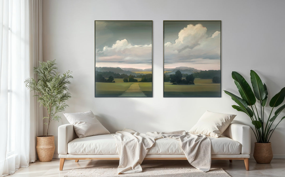 Living room with a white sofa, two framed landscape paintings on the wall, and plants.