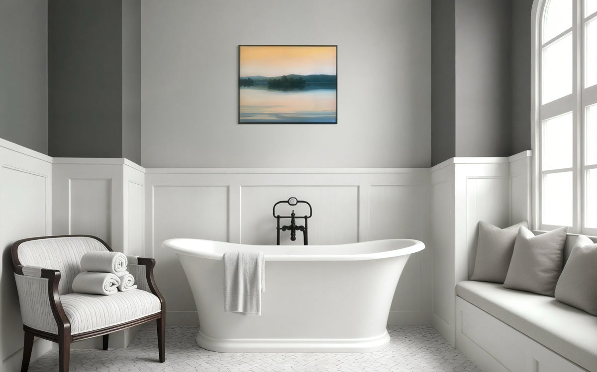 An original painting hangs in a bathroom with a freestanding bathtub, armchair, and window seat.