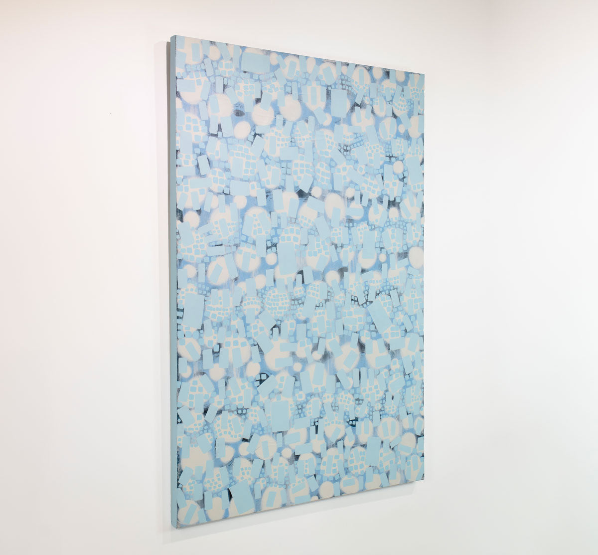 A white and blue abstract painting hangs on a white wall.