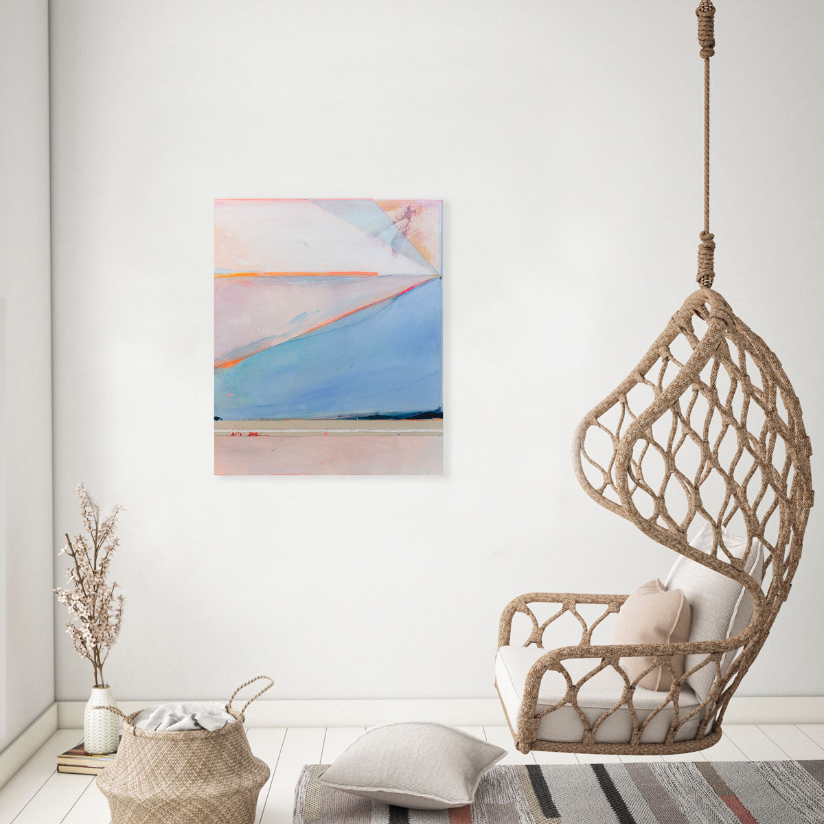 A pink and blue abstract painting hangs on a white wall between a window and a hanging indoor swing seat.