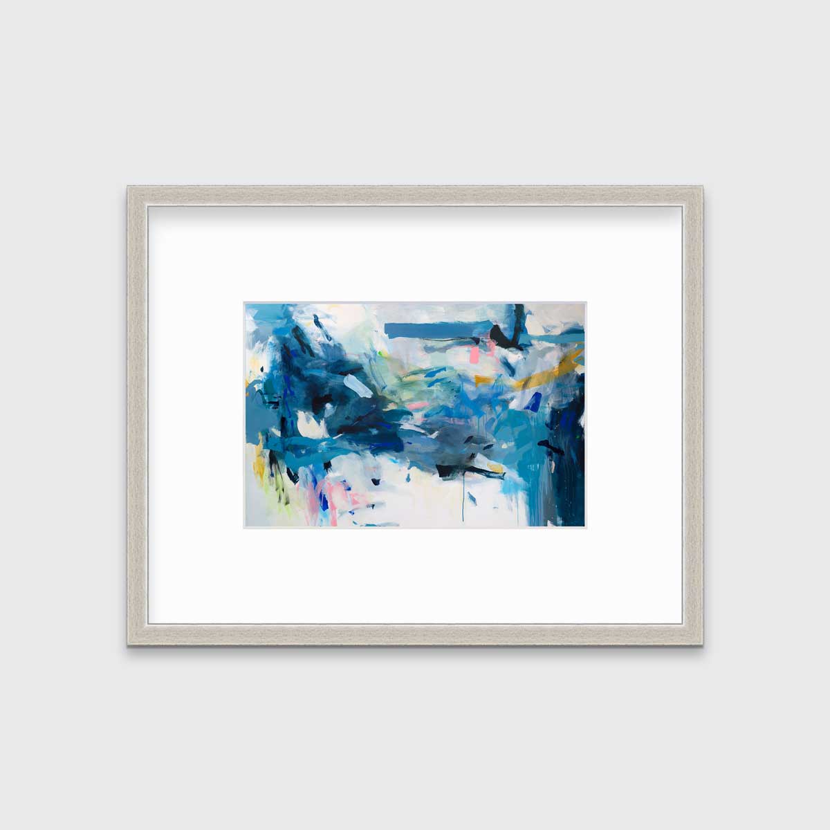 A blue and white abstract print by Kelly Rossetti in a silver frame with a mat hangs on a white wall.