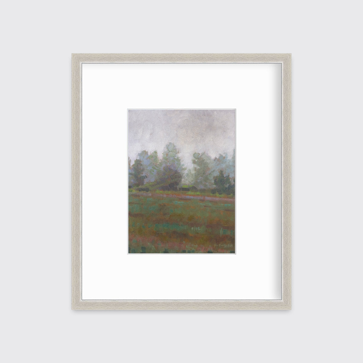 A grey and muted green abstract landscape print in a silver frame with a mat hangs on a white wall.