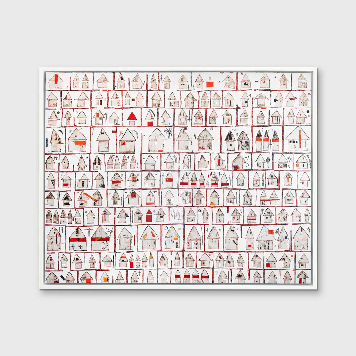 A red and white abstract house print in a white floater frame hangs on a white wall.