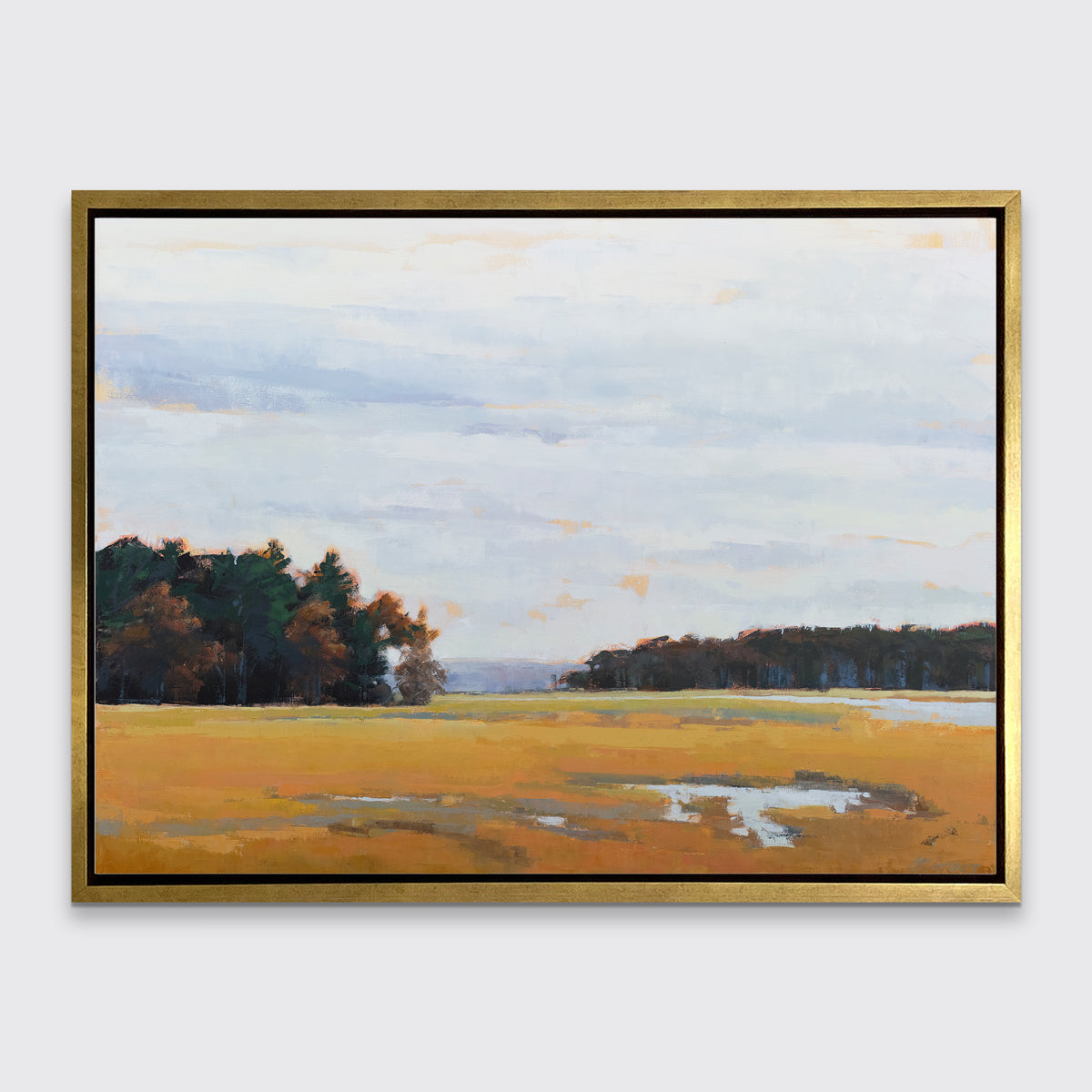 A landscape print in a gold floater frame hangs on a white wall.