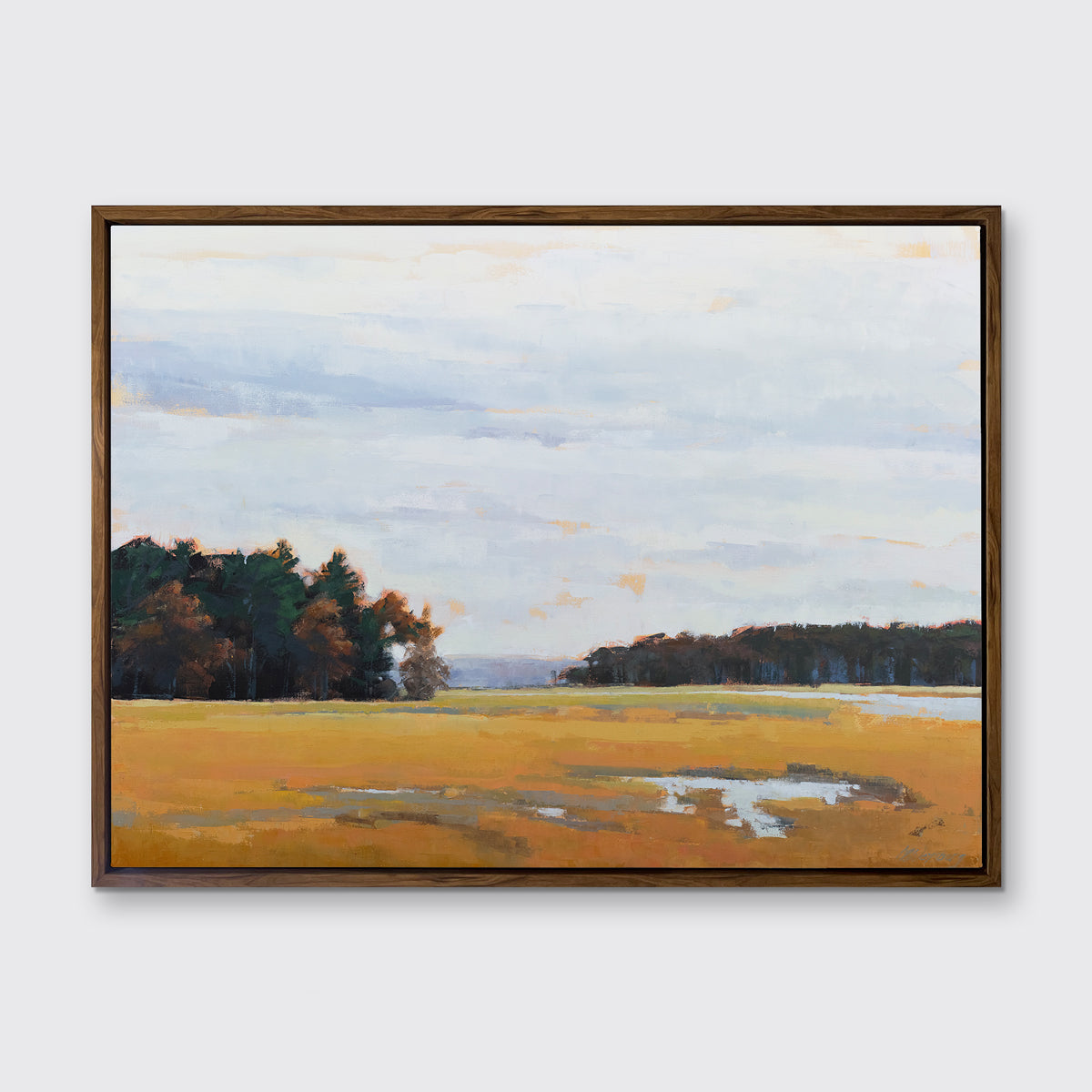 A landscape print in an oak wood floater frame hangs on a white wall.