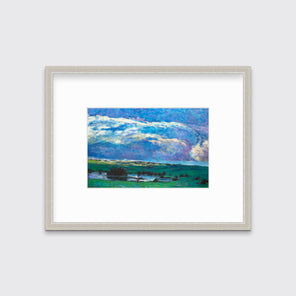 A blue and green abstract landscape print in a silver frame with a mat hangs on a white wall.