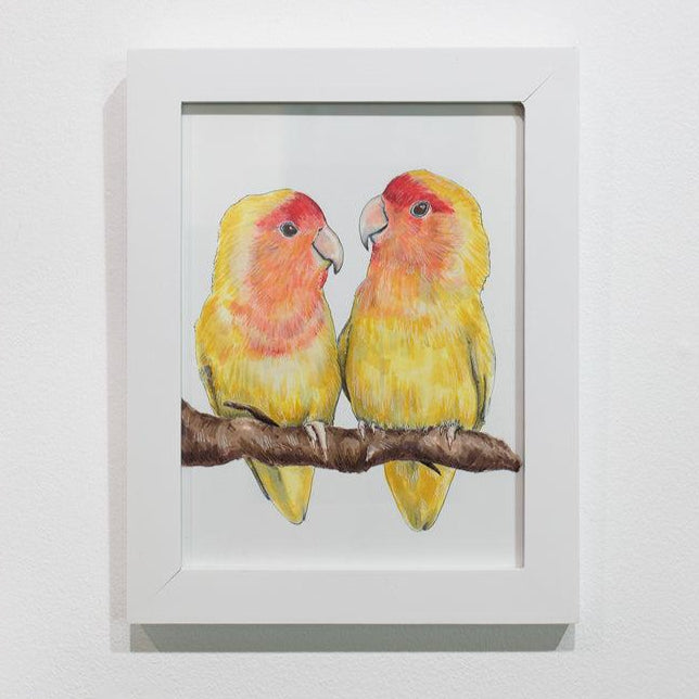 A framed illustration of yellow and orange birds sitting on a branch hangs on a white wall.