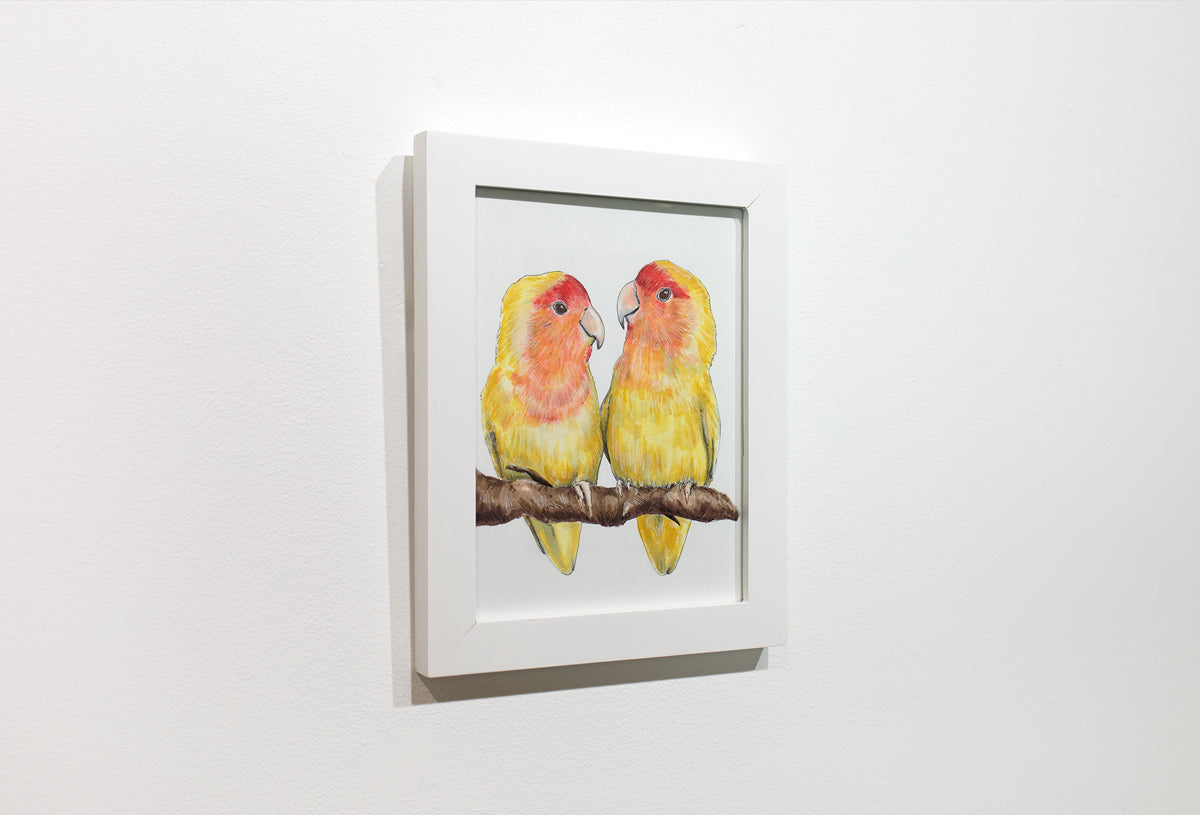 A framed illustration of yellow and orange birds sitting on a branch hangs on a white wall.