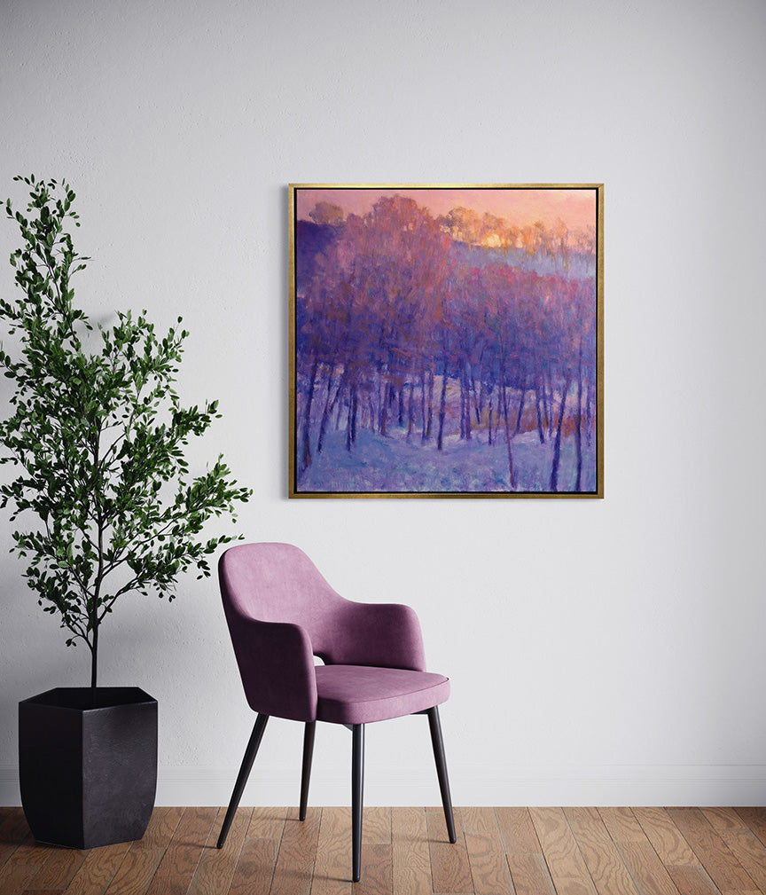 A pink and purple impressionistic landscape hangs on a white wall above a lavender chair and potted tree.