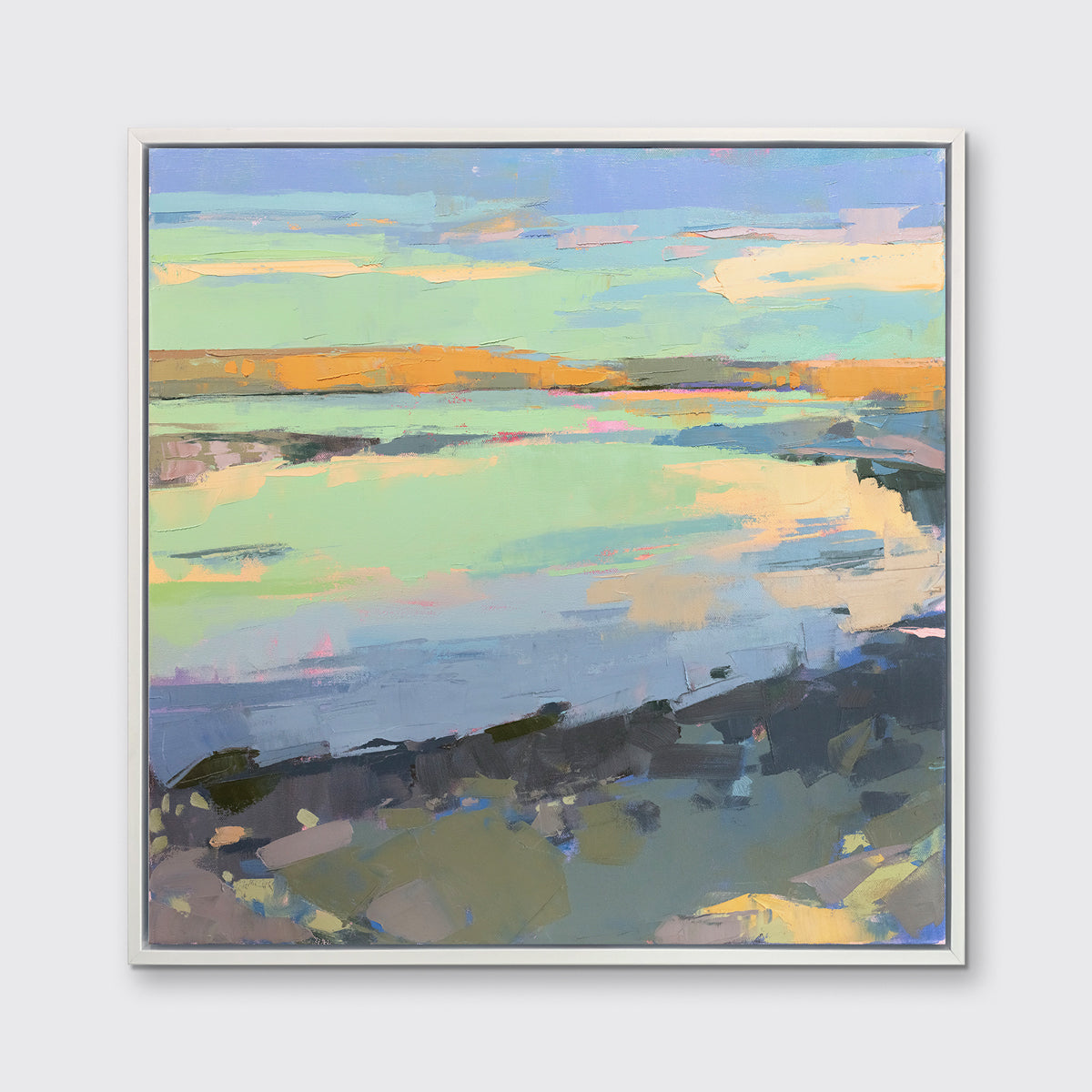 A colorful abstract landscape print framed in a white frame hangs on a white wall.