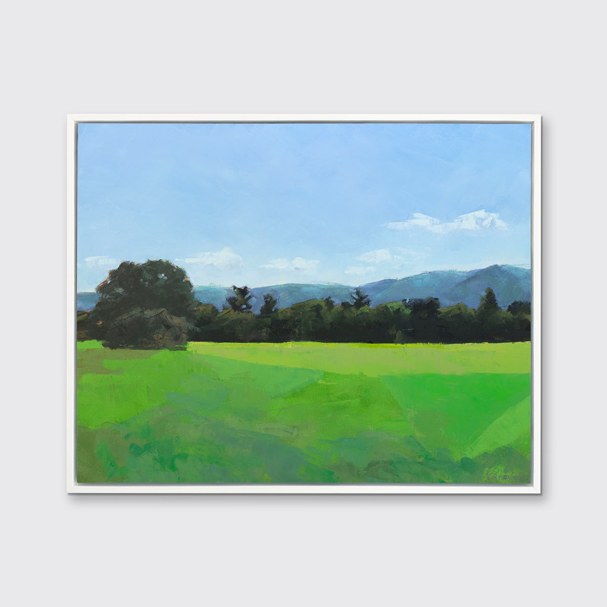 A landscape print in a white floater frame hangs on a white wall.