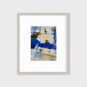 A blue, grey and yellow abstract print in a silver frame with a mat hangs on a white wall.