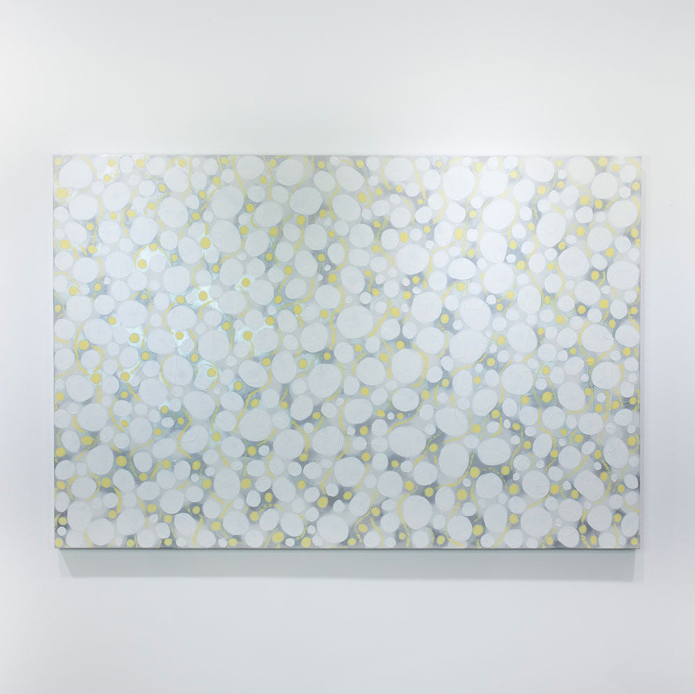 A white, grey, and yellow abstract painting hangs on a white wall.
