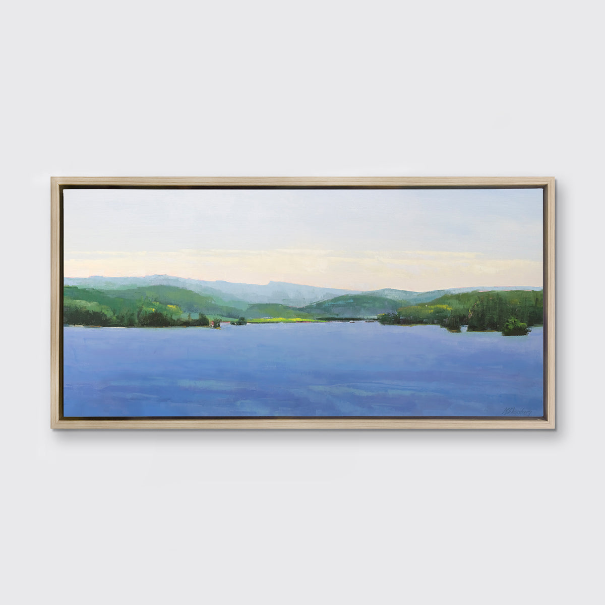 A blue landscape art print framed in a white oak floater frame hangs on a white wall.