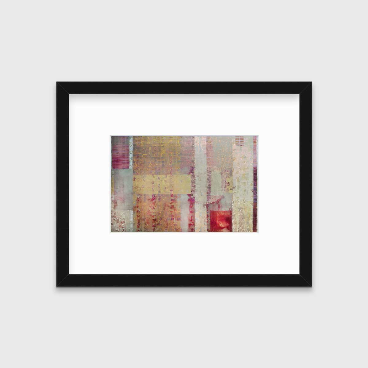 A red, yellow and grey abstract print in a black frame with a mat hangs on a white wall.