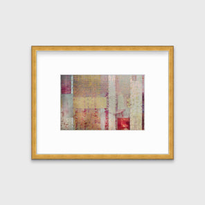A red, yellow and grey abstract print in a gold frame with a mat hangs on a white wall.