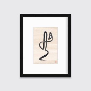 A black minimalistic print by Hazal Ozturk framed in a black frame hangs on a light grey wall.