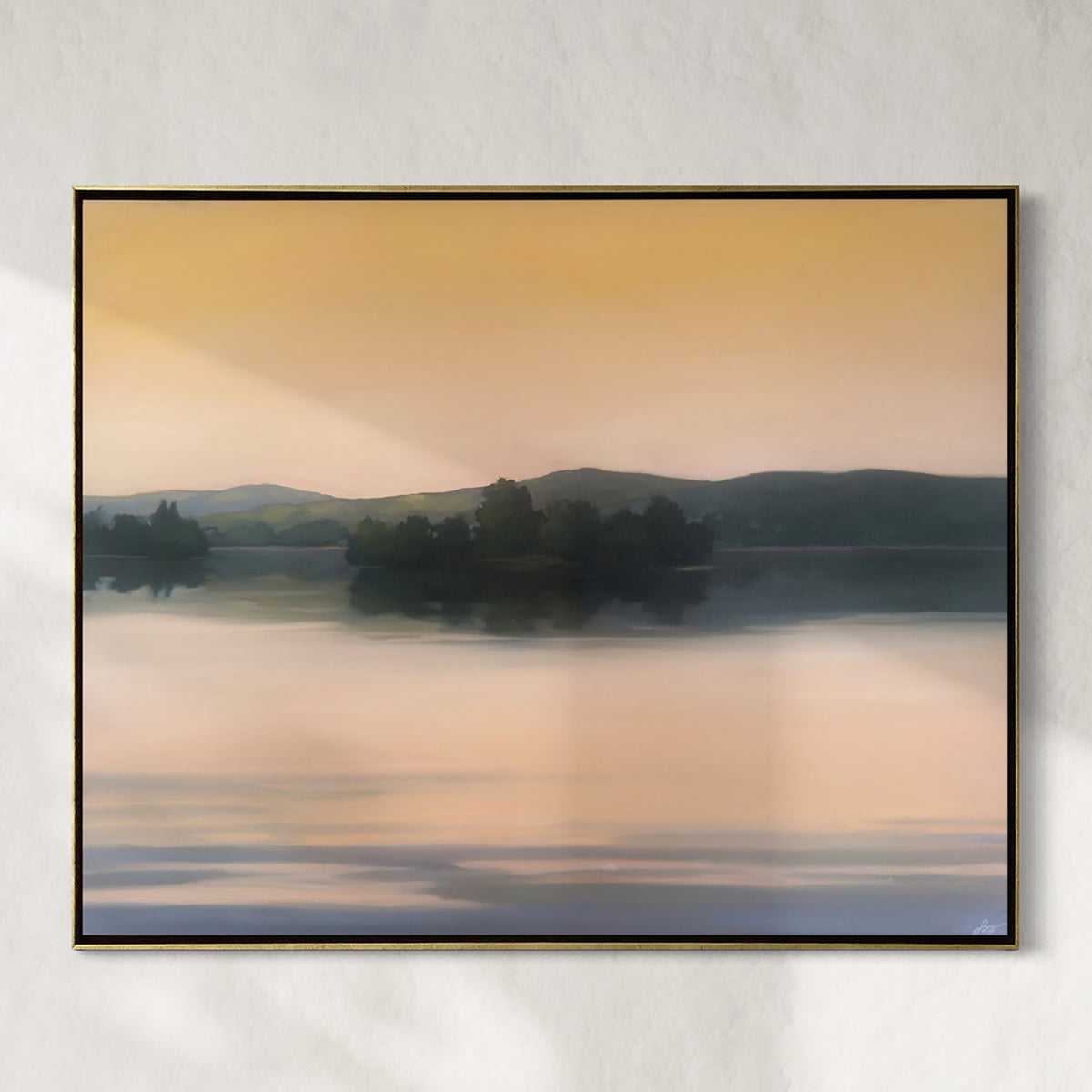 Framed artwork of a landscape with trees and water on a wall.