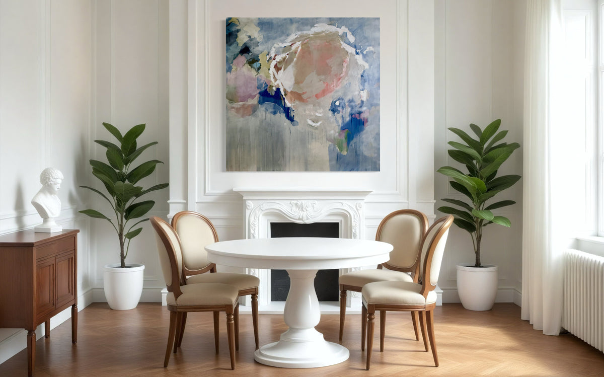 Dining room with a round white table and chairs, abstract painting on the wall, and plants.