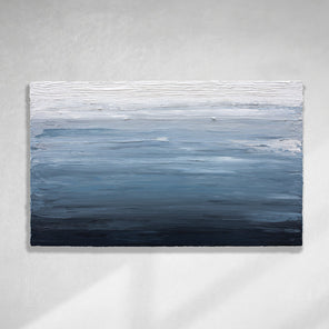 A dark navy blue, light blue, blue, and white thickly textured abstract painting hanging on a white wall in natural light by Teodora Guererra.