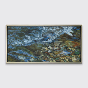 A painting of swirling water in a rocky riverbed hangs in a silver frame on a white wall.