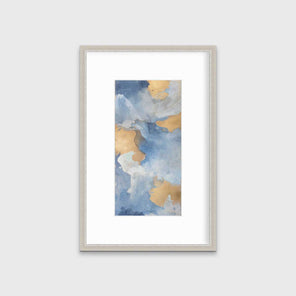 A blue, teal, beige and gold abstract print in a silver frame with a mat hangs on a white wall.