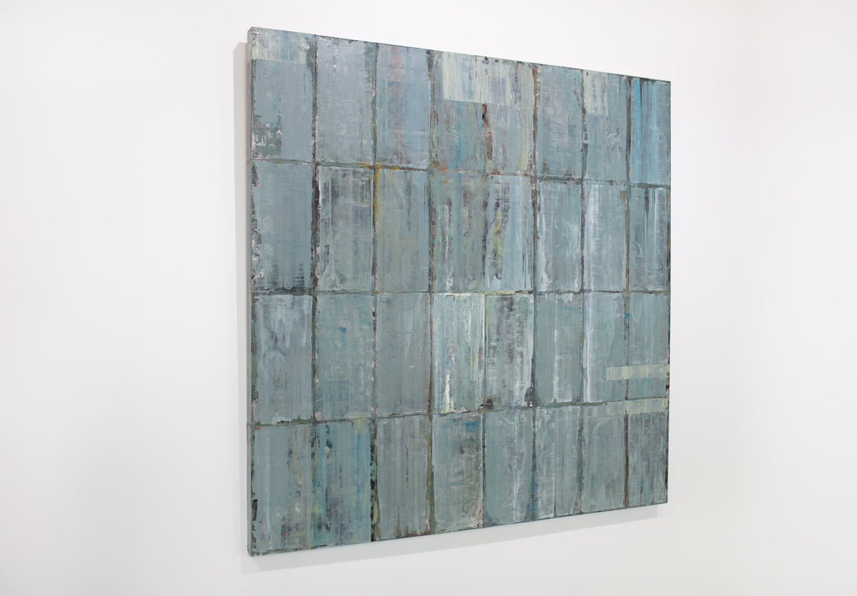 A blue and grey abstract geometric painting hangs on a white wall.