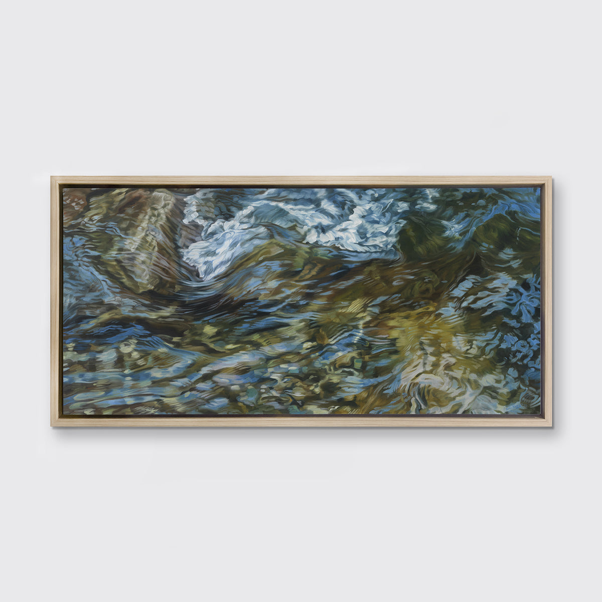 A painting of flowing water in a rocky riverbed in a white oak frame hangs on white wall.