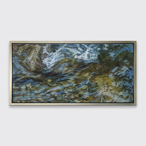 A painting of flowing water in a rocky riverbed in a silver frame hangs on white wall.