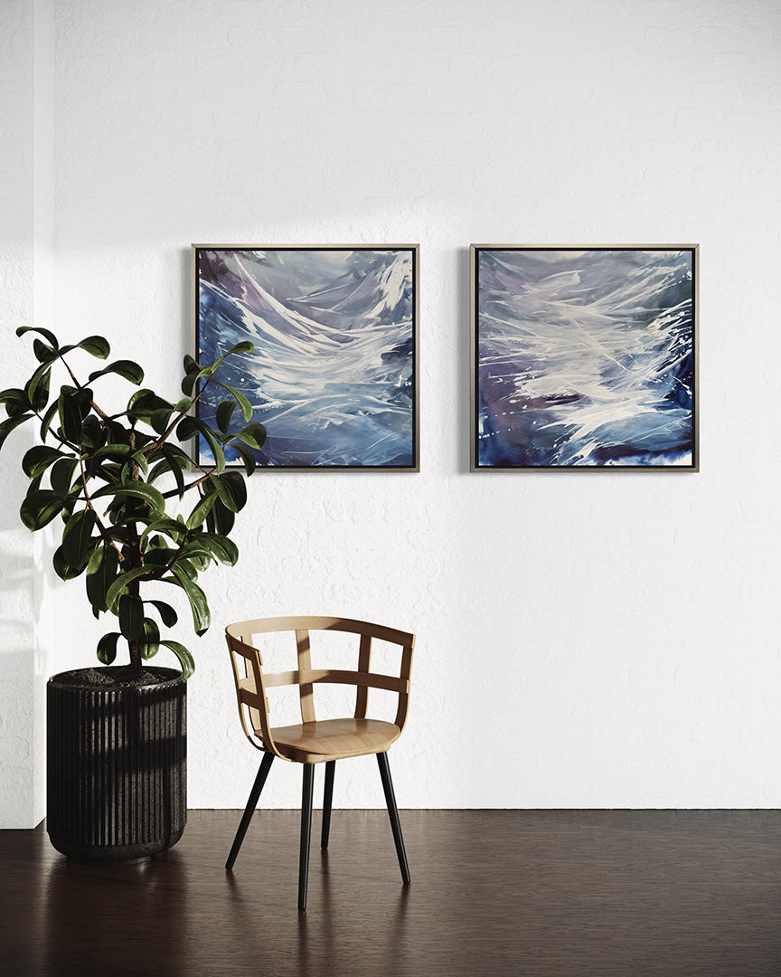 2 blue, white, and lavender prints framed in silver floater frames hang on a white wall with a chair and large potted plat in front.