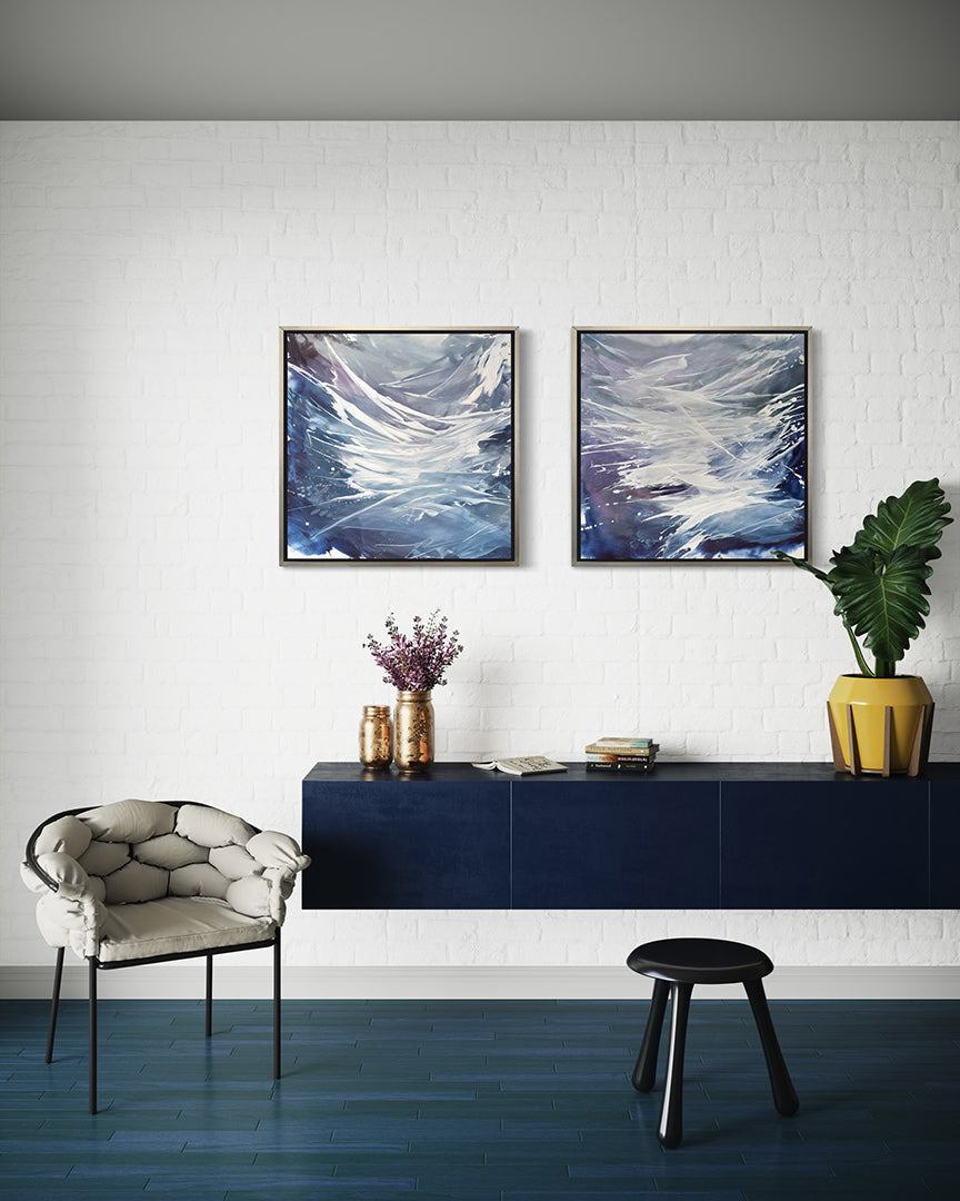 2 blue, white, and lavender prints framed in silver floater frames hang over a blue credenza with decorative objects.