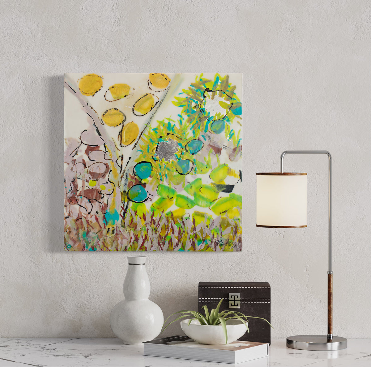 A yellow, green, and pink abstract painting hangs on a textured white wall above a white marble table top with white table decor and a table lamp.