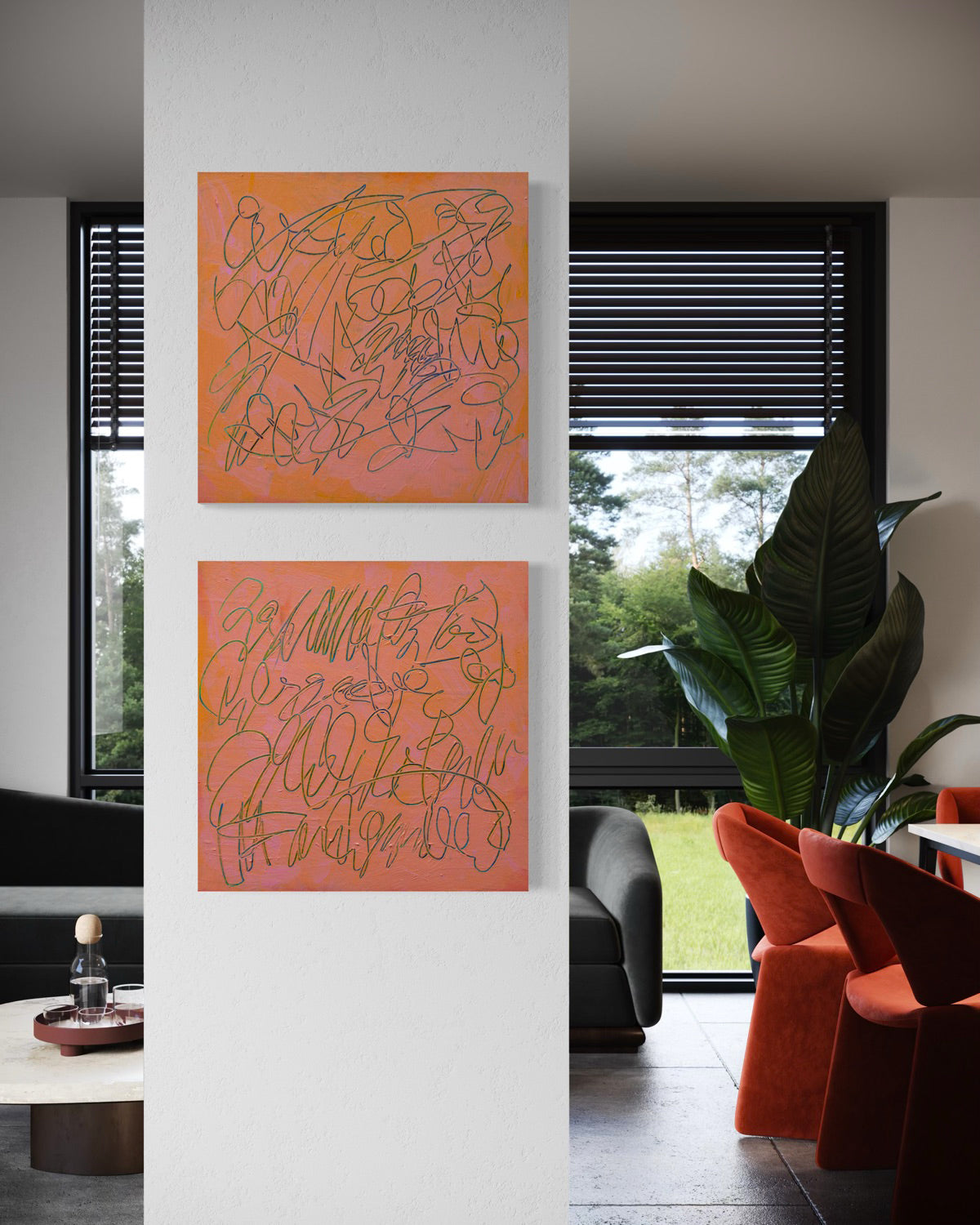 Two abstract text based paintings in orange and pink tones hanging vertically on a white wall in a modern living room setting.
