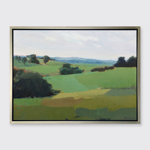 A green limited edition landscape print in a silver frame hangs on a white wall. 