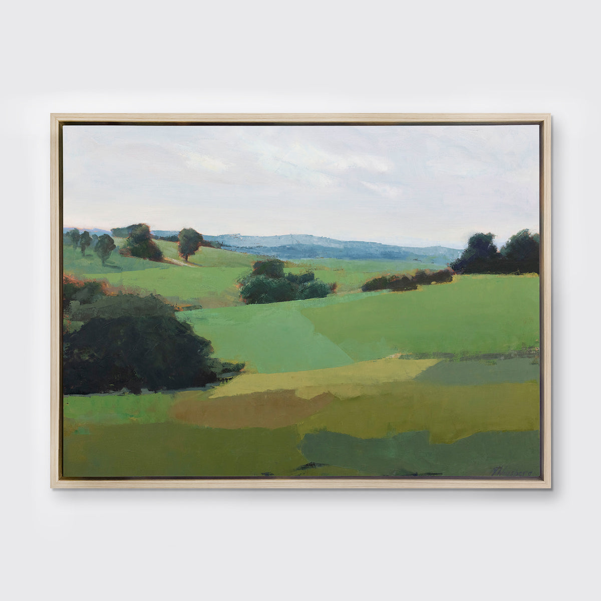 A green limited edition landscape print in a light wood floater frame hangs on a white wall.