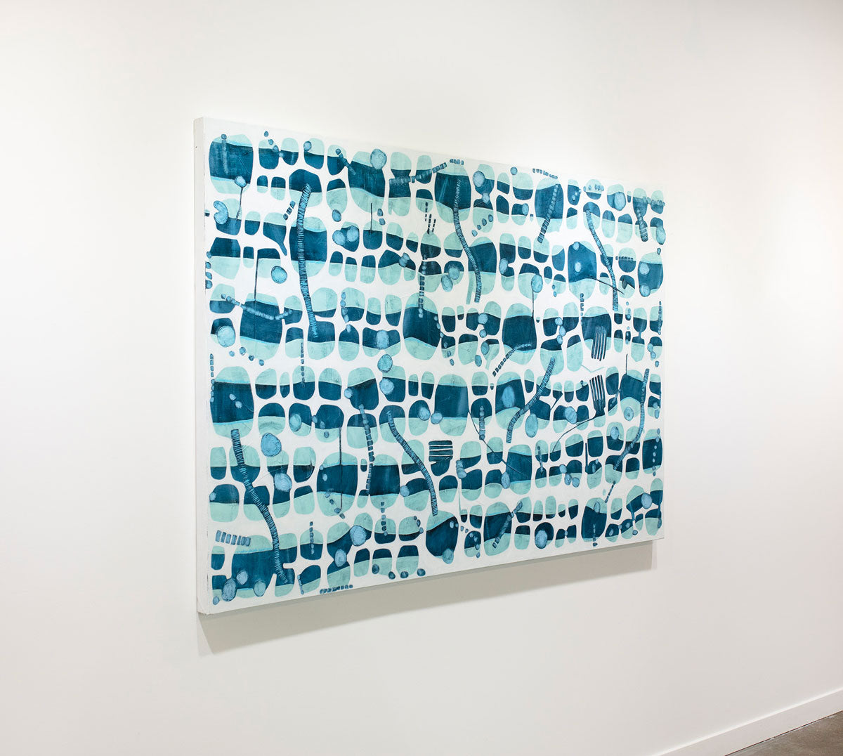 A blue and white abstract painting hangs on a white wall.