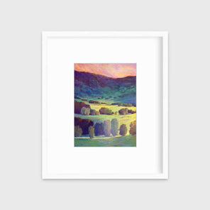 A pink, blue and green landscape print in a white frame with a mat hangs on a white wall.