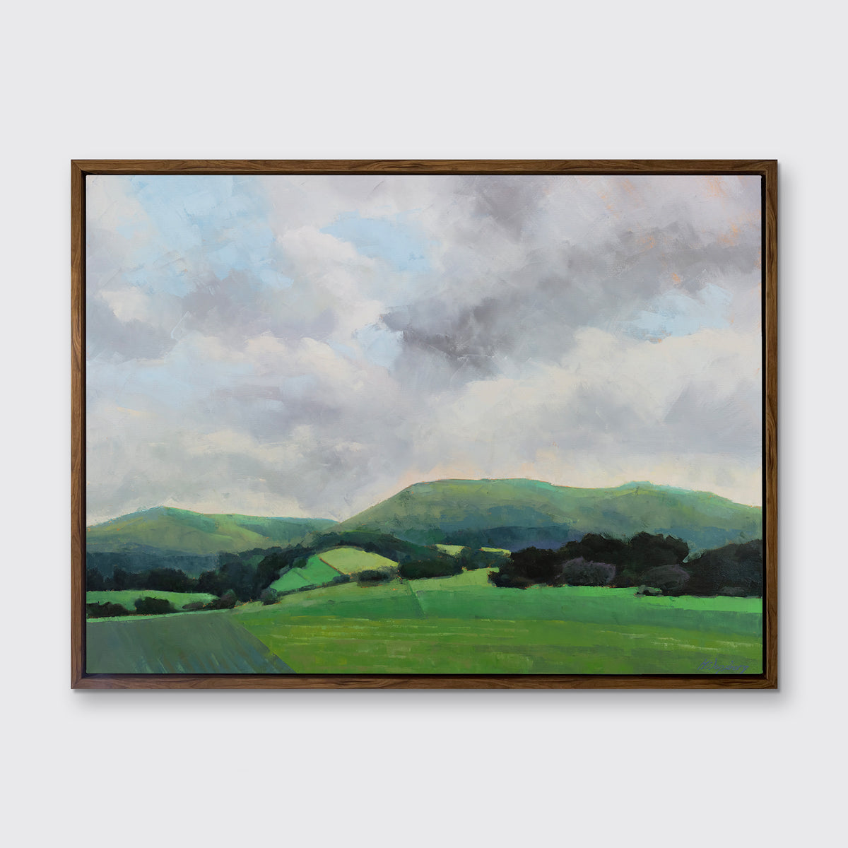 A landscape print in an oak wood floater frame hangs on a white wall.