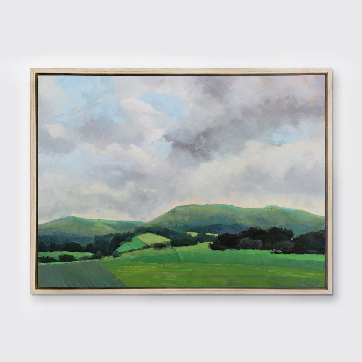 A landscape print in a white oak wood floater frame hangs on a white wall.