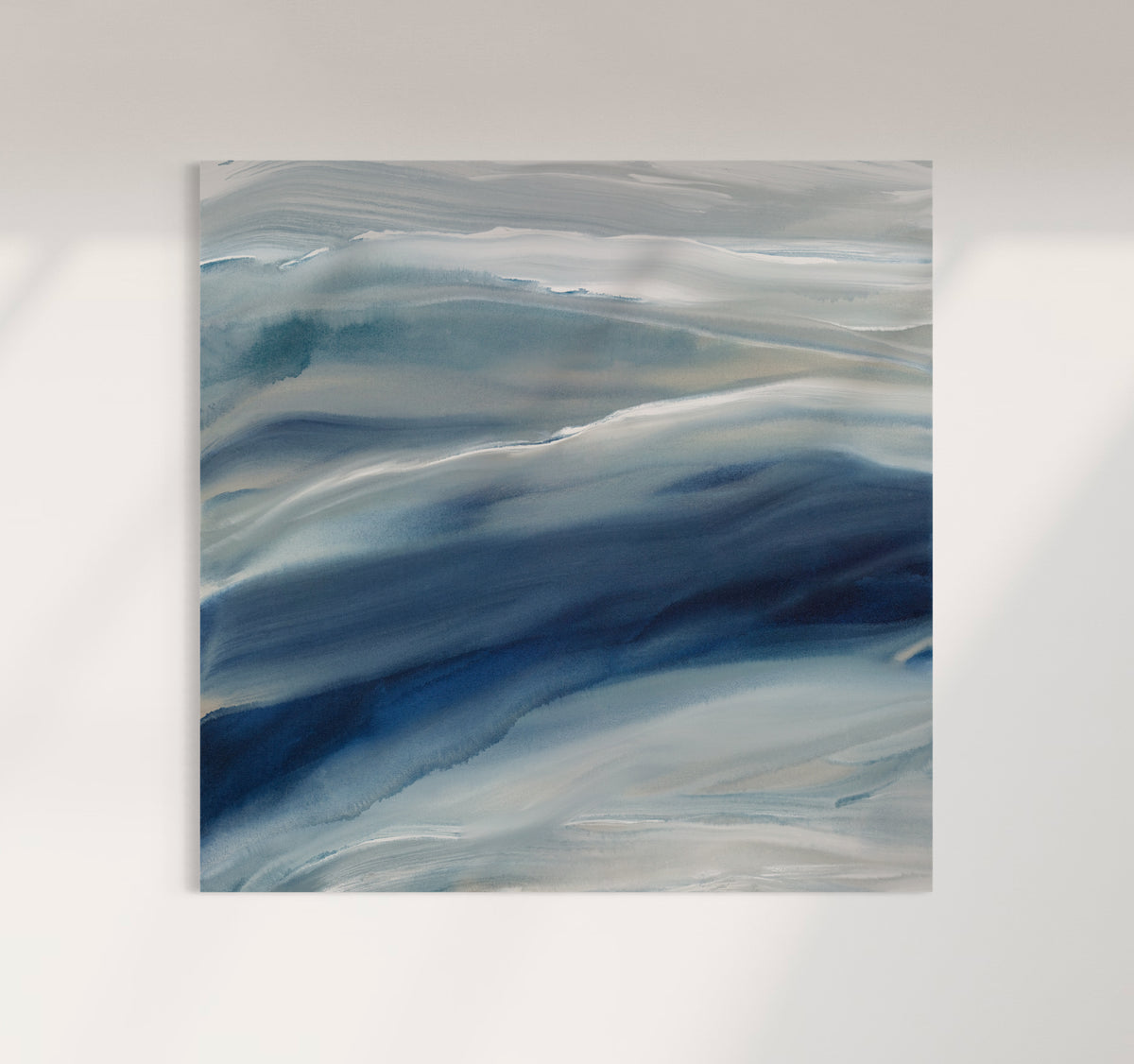 A blue, teal, beige and white abstract canvas print stretched on stretcher bars hangs on a white wall.