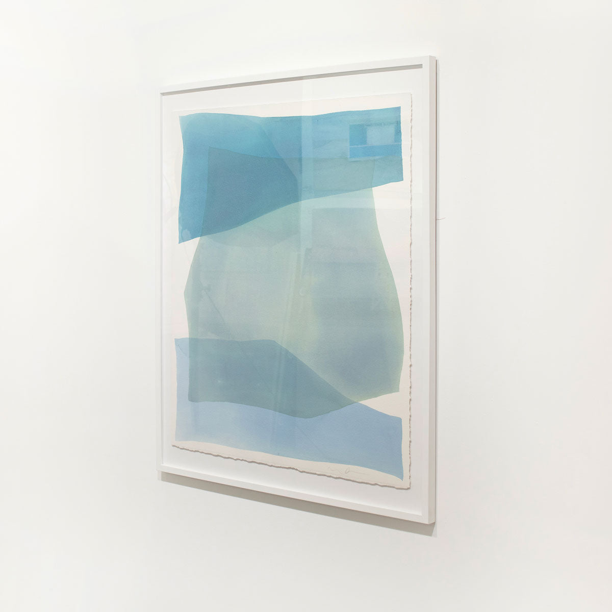A framed blue abstract watercolor painting hangs on a white wall.