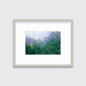 A blue, purple and green abstract print in a silver frame with a mat hangs on a white wall.