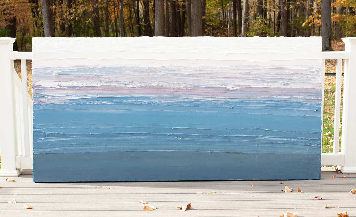 A blue, lavender and white thickly textured original abstract painting leaning on a deck outside in natural light by Teodora Guererra.