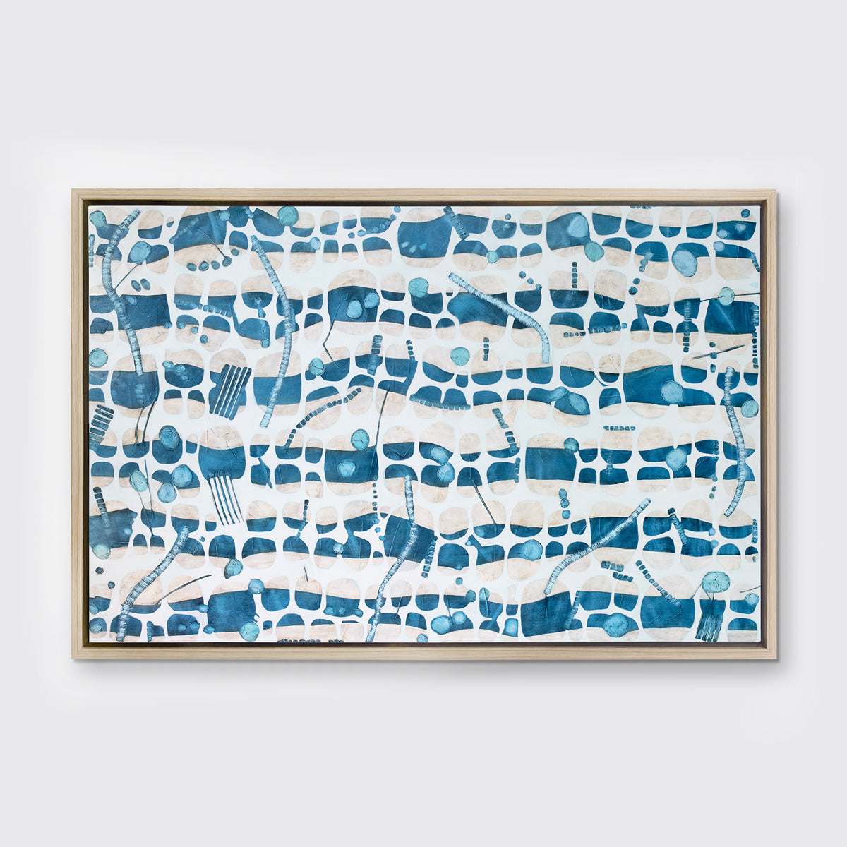 A blue, teal and beige geometric abstract print in a white oak wood floater frame hangs on a white wall.
