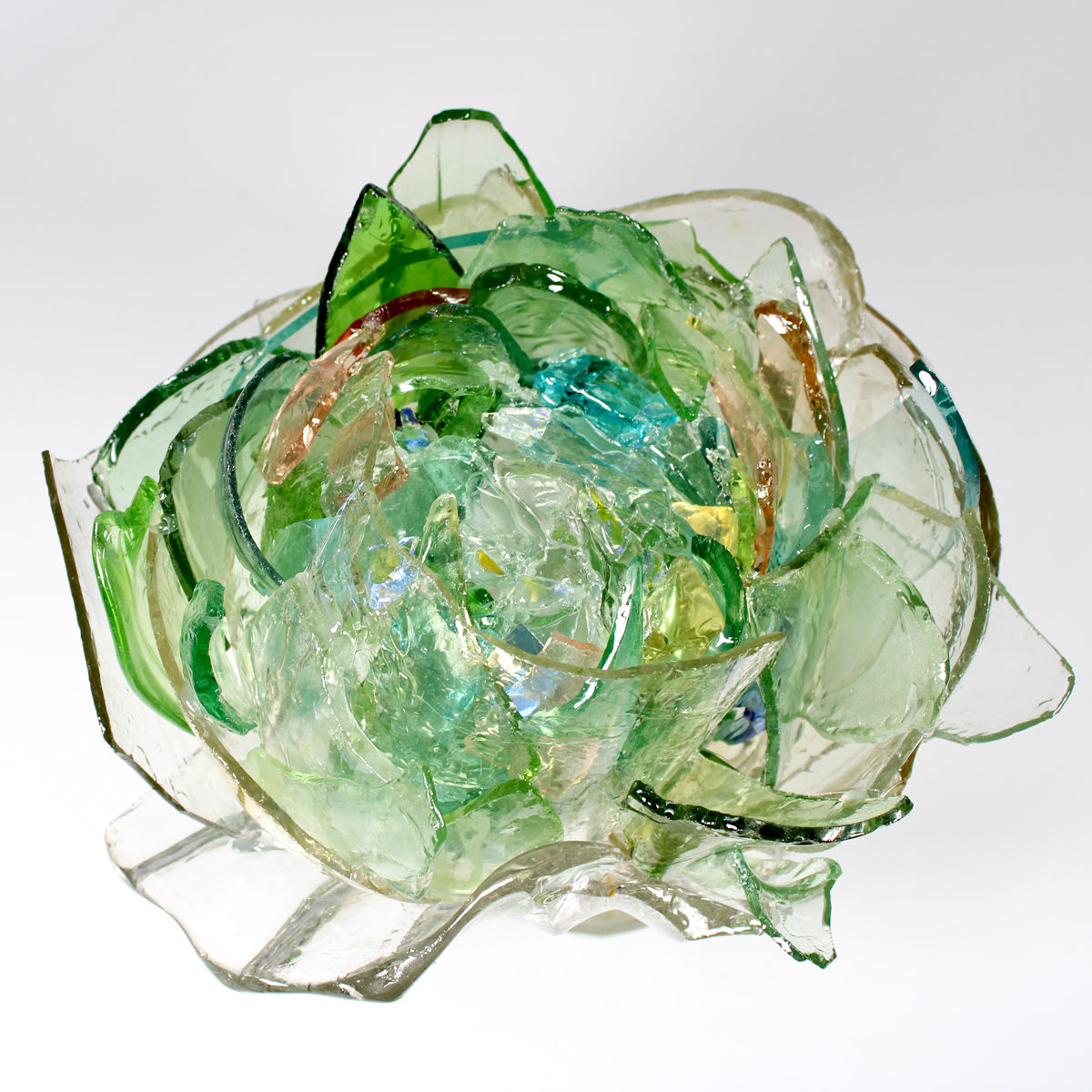 Artistic glass sculpture with green and clear colors on a white background.