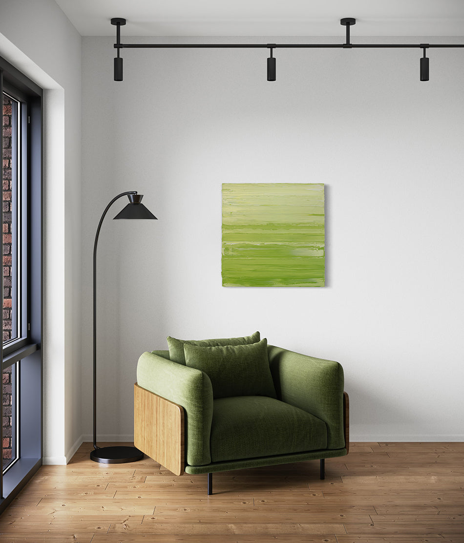 A chartreuse green and white textured abstract painting by Teodora Guererra hangs on a wall over a fabric green chair with a black modern floor lamp to the left.
