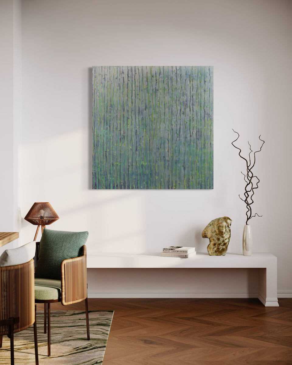 An abstract painting with purple and green undertones and striated with silver lines hangs on a wall over a white credenza with book, gold sculpture and vase with decorative twigs. Chairs with green pillows are to the left.