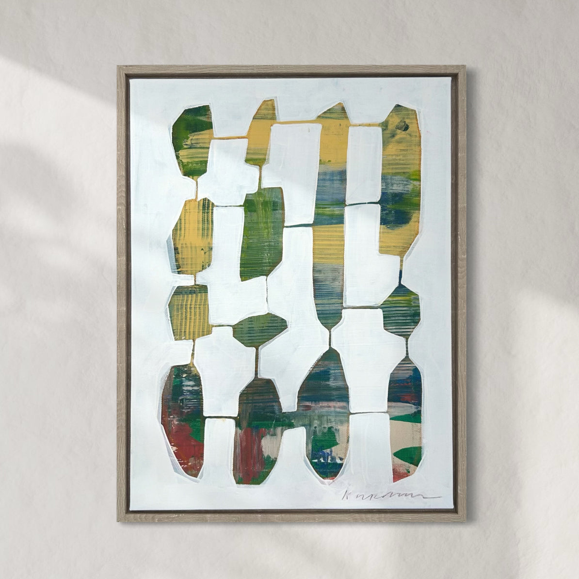 A framed abstract painting featuring geometric shapes in various colors displayed on a wall.