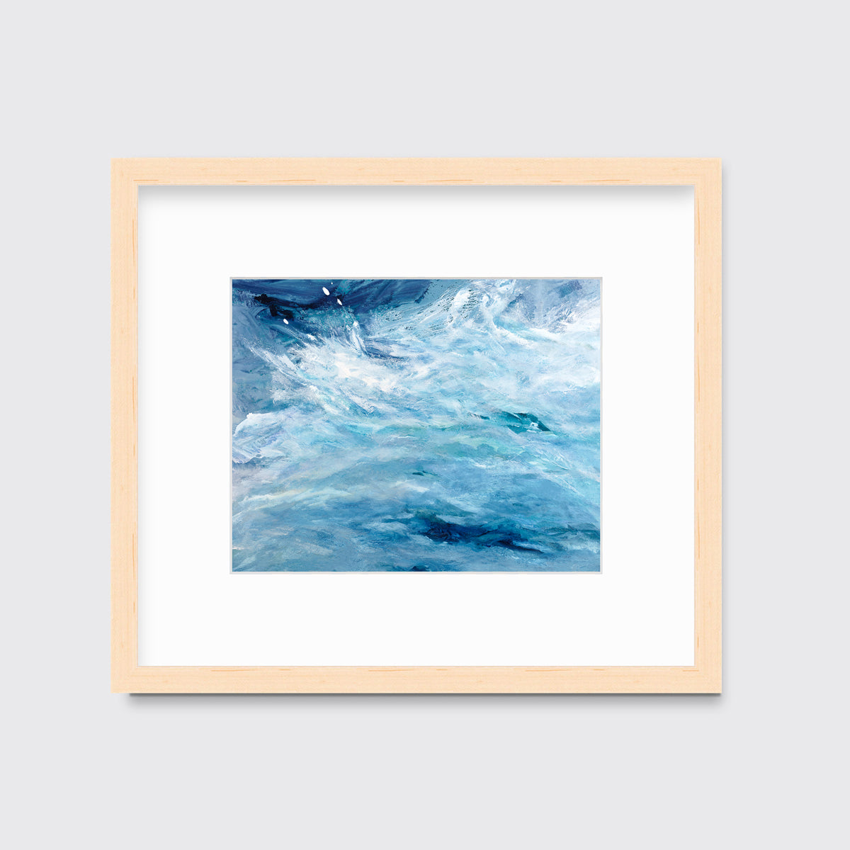 A blue, teal and white abstract print in a natural wood frame with a mat hangs on a white wall.