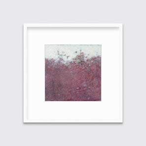 A dark red abstract landscape print in a white frame with a mat hangs on a white wall.
